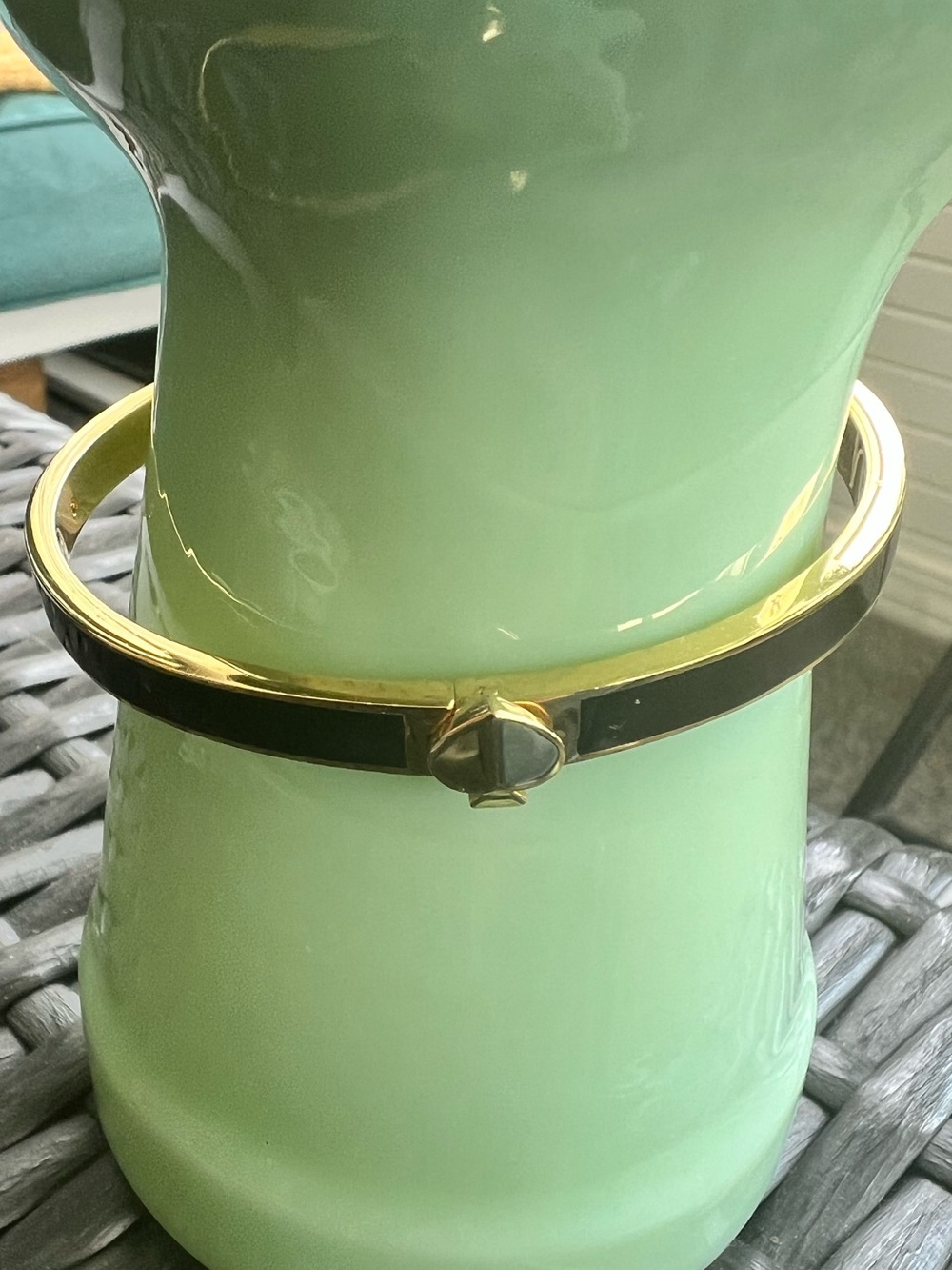 Kate Spade metal hinged bangle bracelet with black enamel inlay and gold trim.